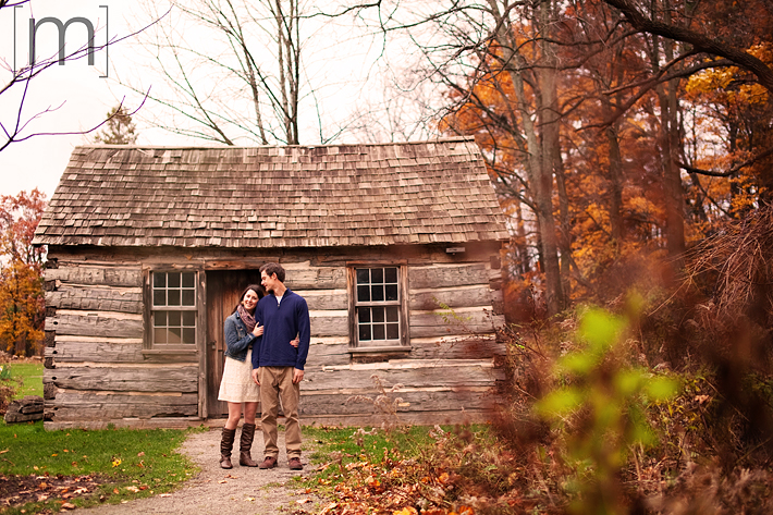a photo of a couple cuddling against a rustic barn at a fall engagement photoshoot in balls falls